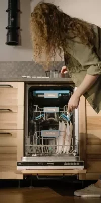 Photo of a person loading a dishwasher with plates