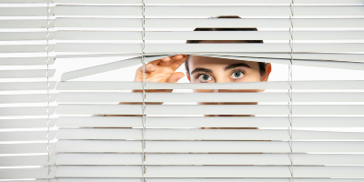Person looking through a venetian blind