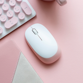 Photo of a white computer mouse on a pink desk