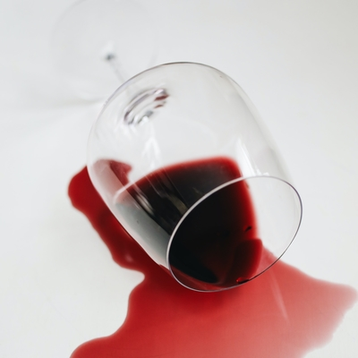 Photo of a full red wine glass that has been knocked over