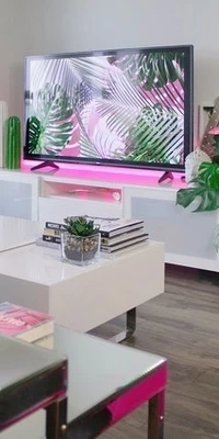 Photo of a television on a white cabinet with pink backlighting.