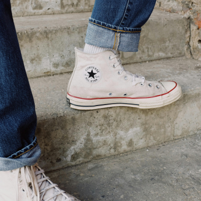Photo of a persons feet, wearing white converse on concrete steps