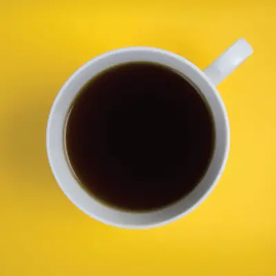 Birds-eye view photo of a coffee cup on a yellow desk