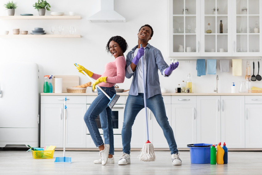 Two people cleaning the kitchen and singing joyfully