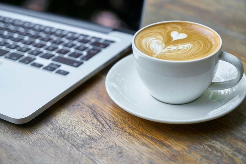 Coffee cup next to laptop