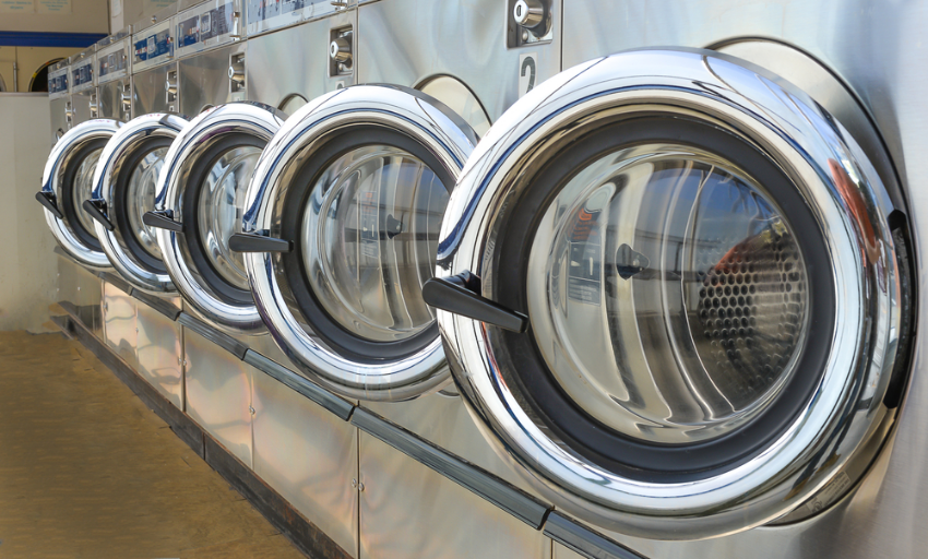 A row of commercial washing machines with their doors open
