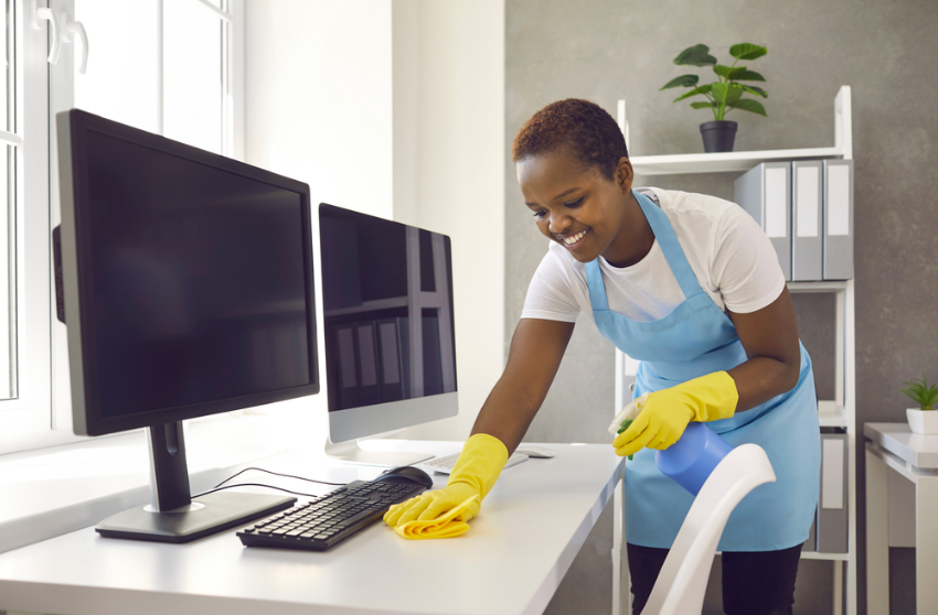 Lady cleaning a desk with keyboard