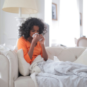 Lady sat on a sofa blowing their nose