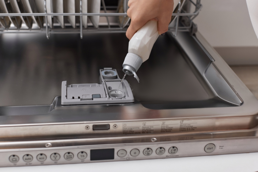 Lady adding rinseaid into the dishwasher