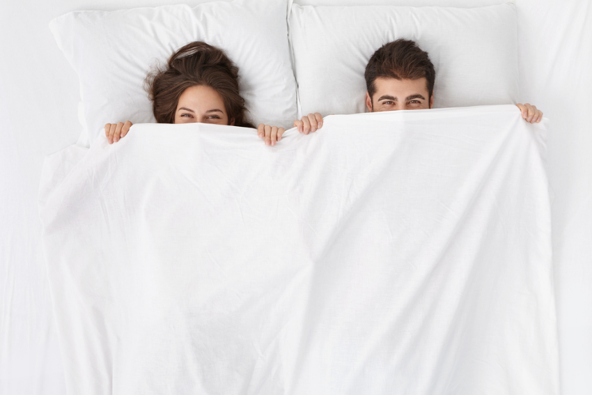 Couple in bed with faces covered