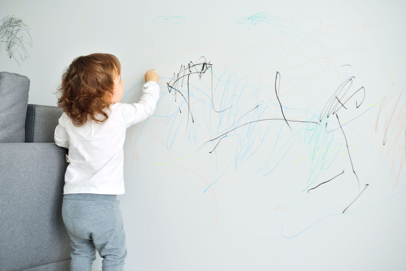 Child scrawling on wall with crayon