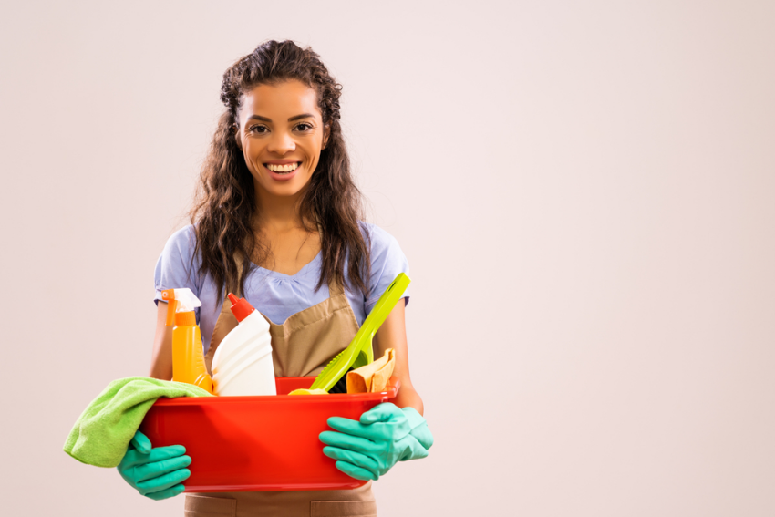 Lady holding a bucket containing cleaning supplies